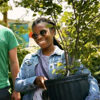 woman in sunglasses carrying a tree