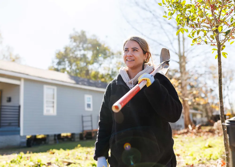 a person holding a shovel ready to plant trees