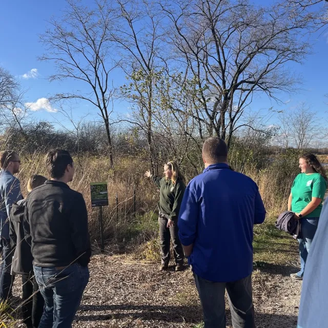 A group of individuals standing near a sign in a wooded area.