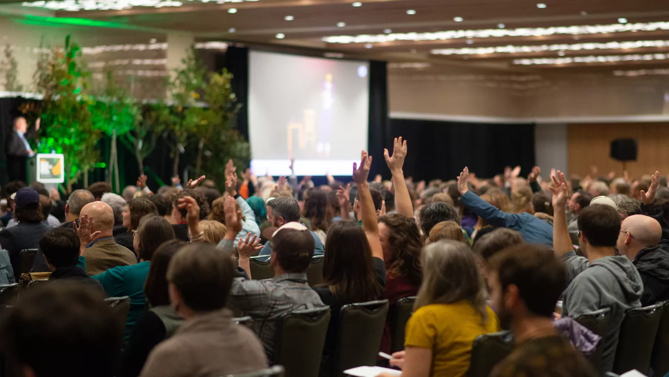 Crowd of people raising hands in answer to speaker