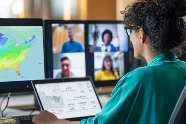 woman looking at multiple computer screens, participating in a webinar.