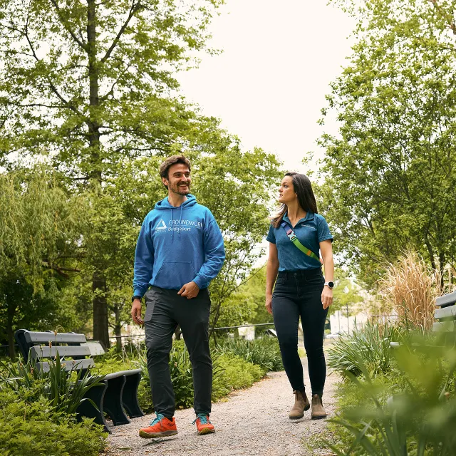 A planter partner volunteer and an Arbor Day Foundation associate talking while walking along tree-lined path.