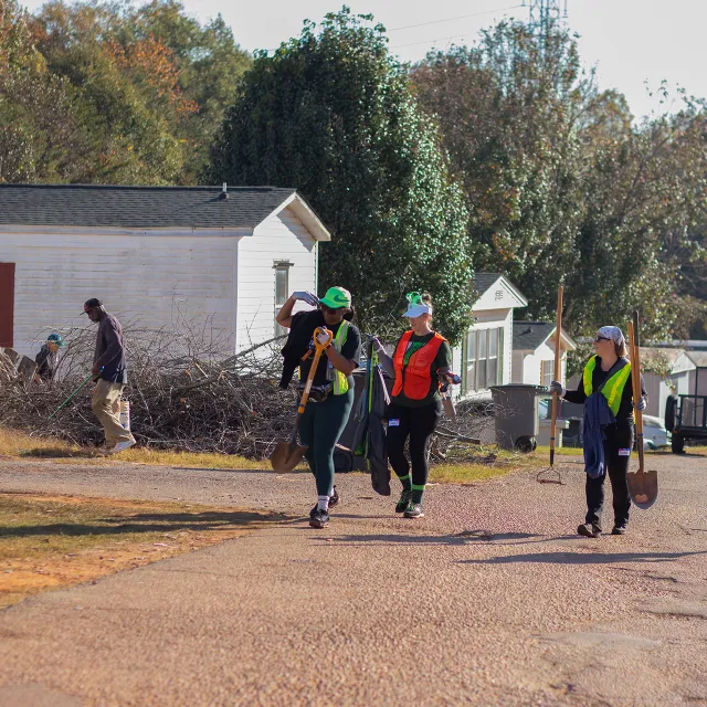 Volunteers carry shovels and clean up storm debris and fallen tree limbs.