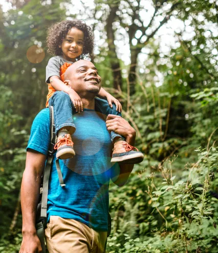 man with young boy in forest