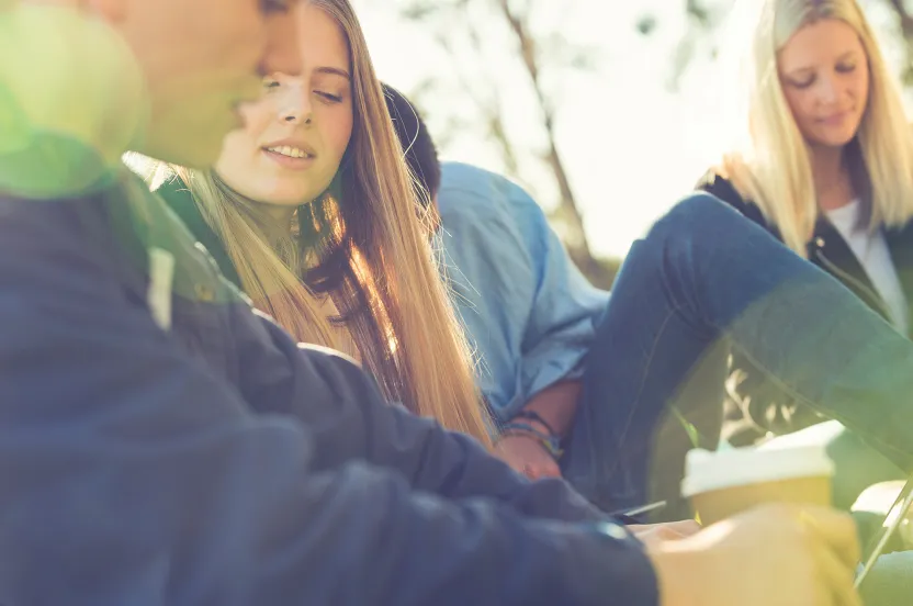 high school students studying outside under shade trees