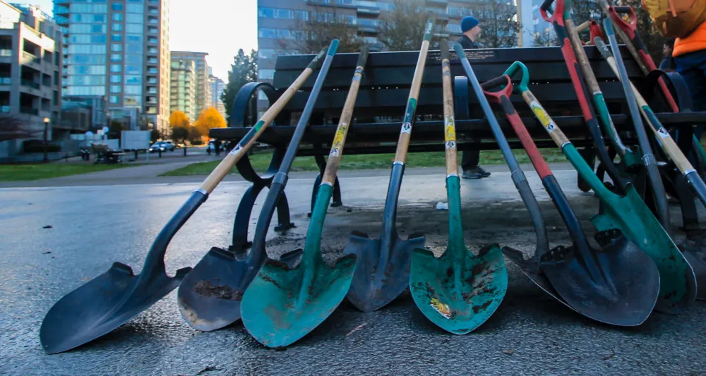 stack of shovels with city skyline in the background