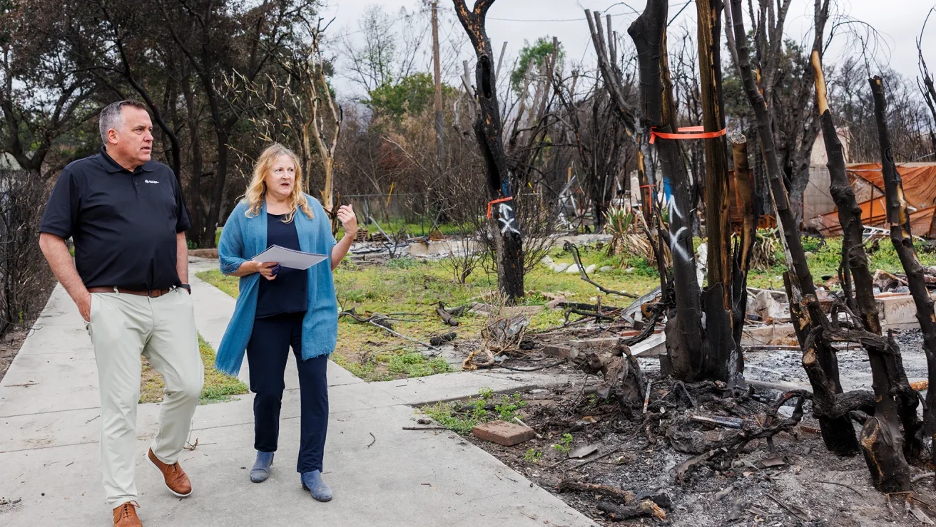 CEO of Arbor Day Foundation walks with a planting partner in Los Angeles through an area devasted by fire.