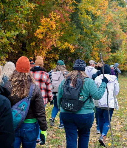 group of people walking outside under fall trees