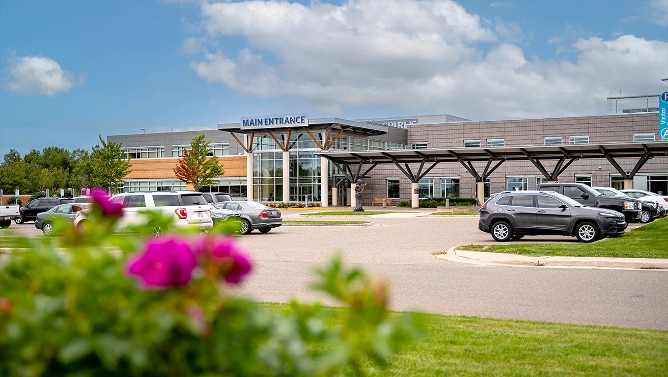 A view of the Aspirus Hospital building, floral bush in the foreground.