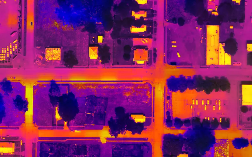 Aerial view of a suburban area with colorful heat maps highlighting buildings, vehicles, and green spaces in vibrant purple and orange hues.