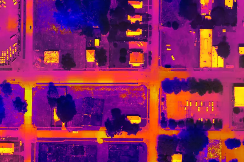 Aerial view of a suburban area with colorful heat maps highlighting buildings, vehicles, and green spaces in vibrant purple and orange hues.