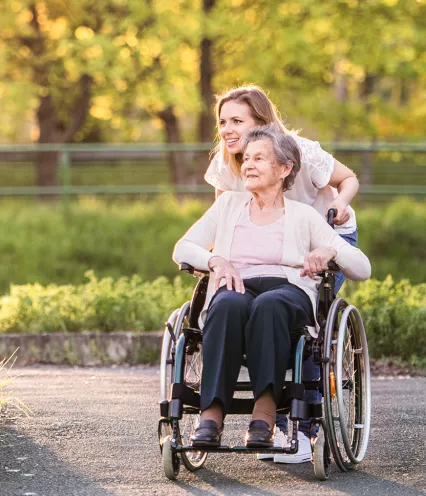 woman pushing elderly woman in wheelchair