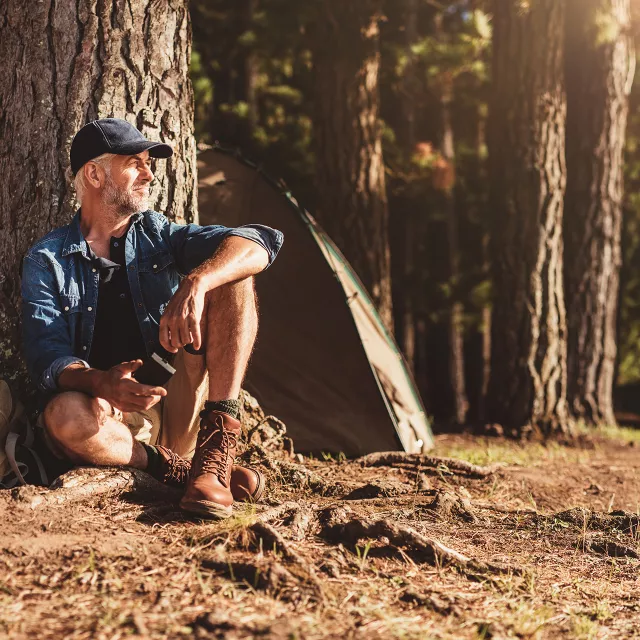 man resting by a tree in the forest